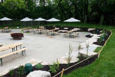 Gravel hardscape with intimate flagstone patio spaces, garden beds, and lush grass border.