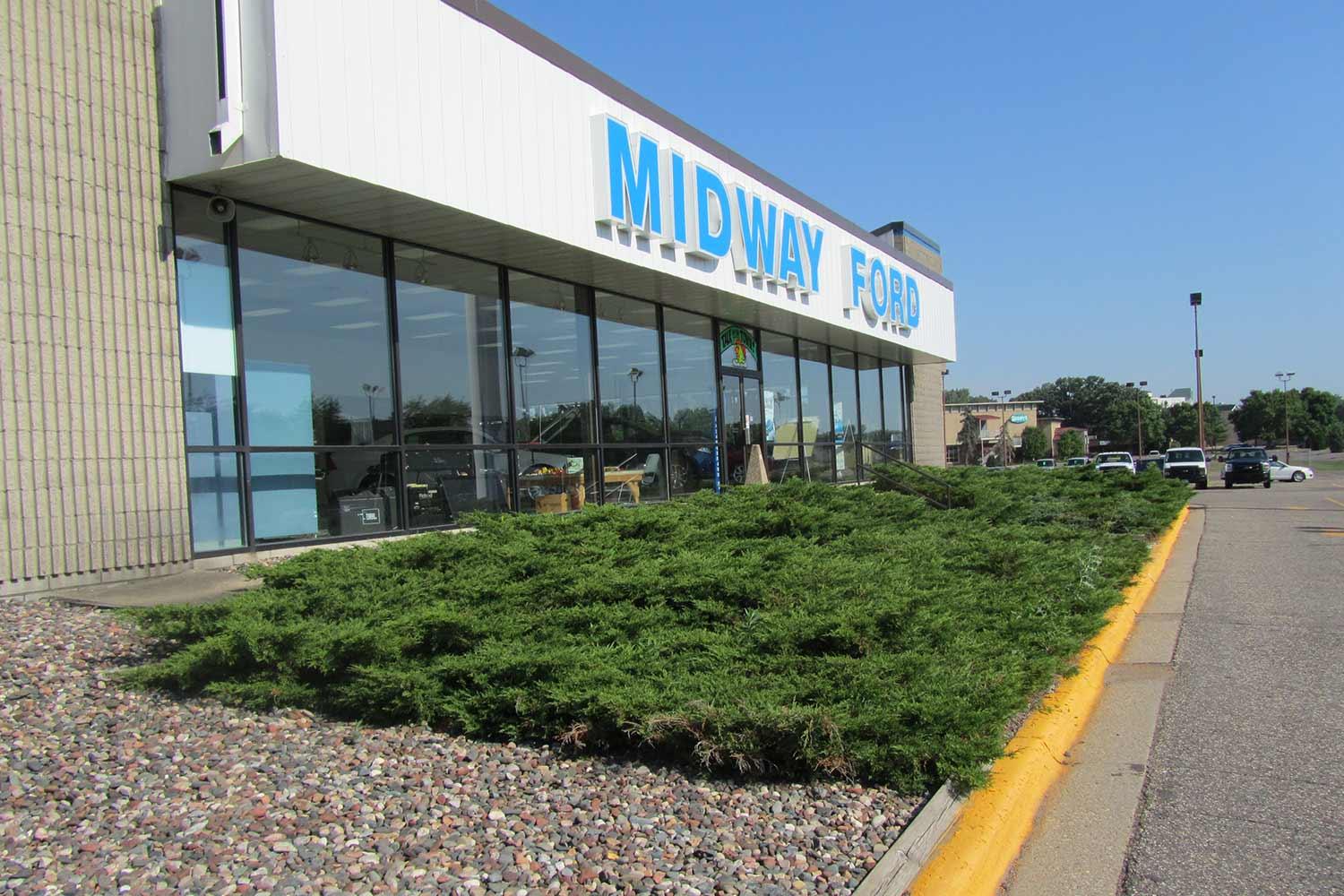 Midway Ford front entry before. Low evergreen shrubs are uninviting.